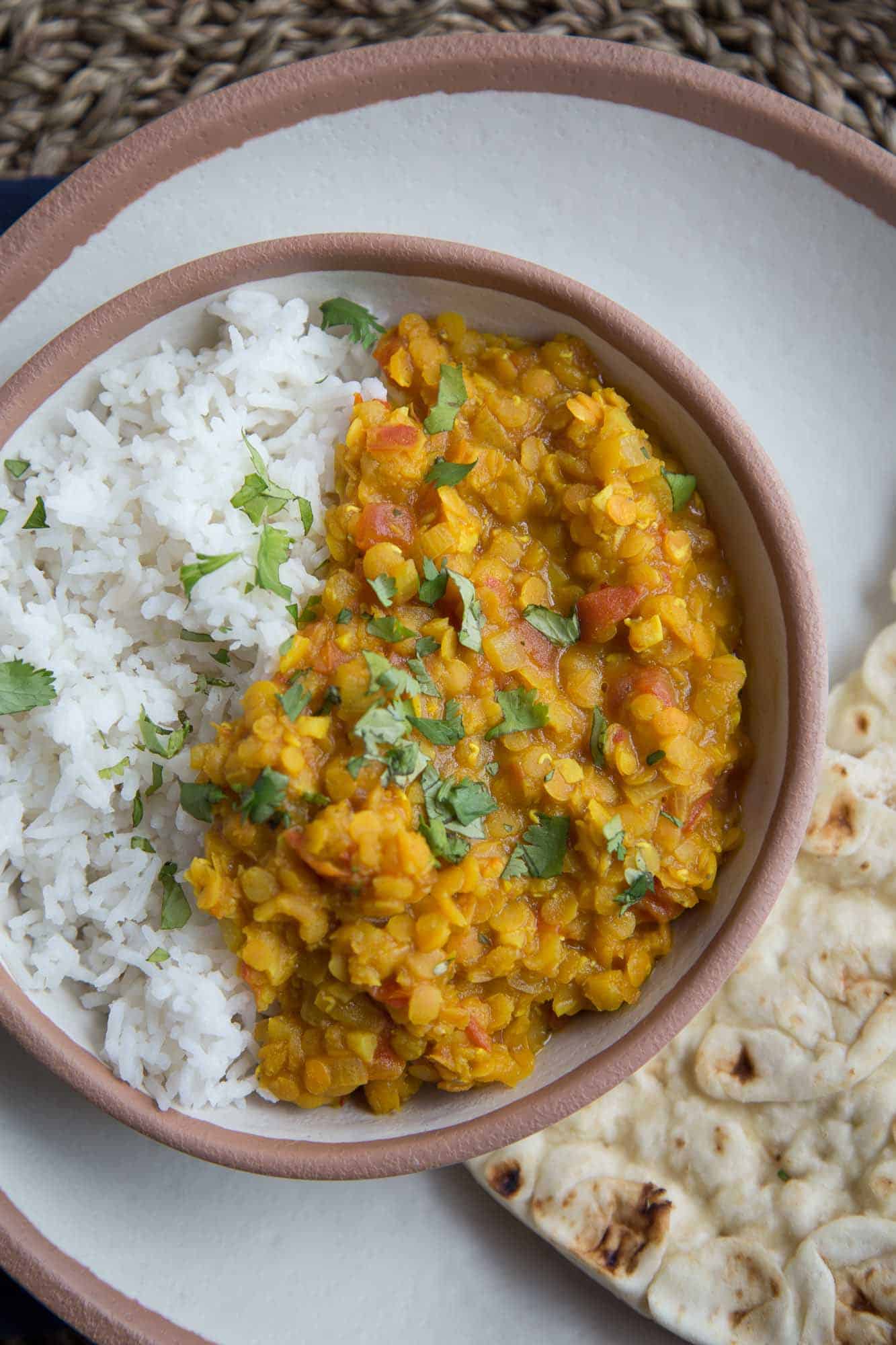 close up of Vegetarian Red Lentil Dal in a bowl with a side of naan.