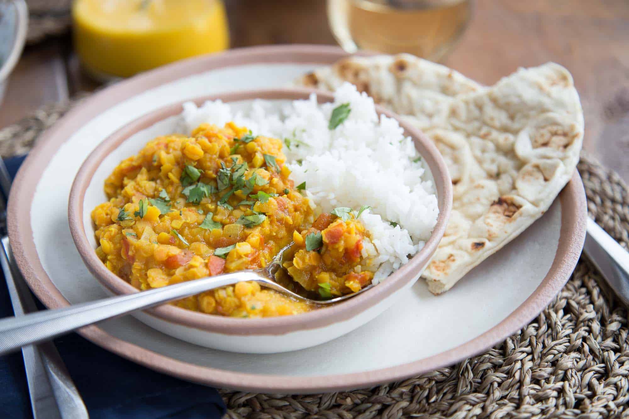 Vegetarian Red Lentil Dal in a shallow bowl with naan next to it.