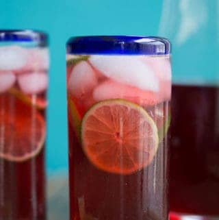 Hibiscus tea in a tall clear glass with a blue rim