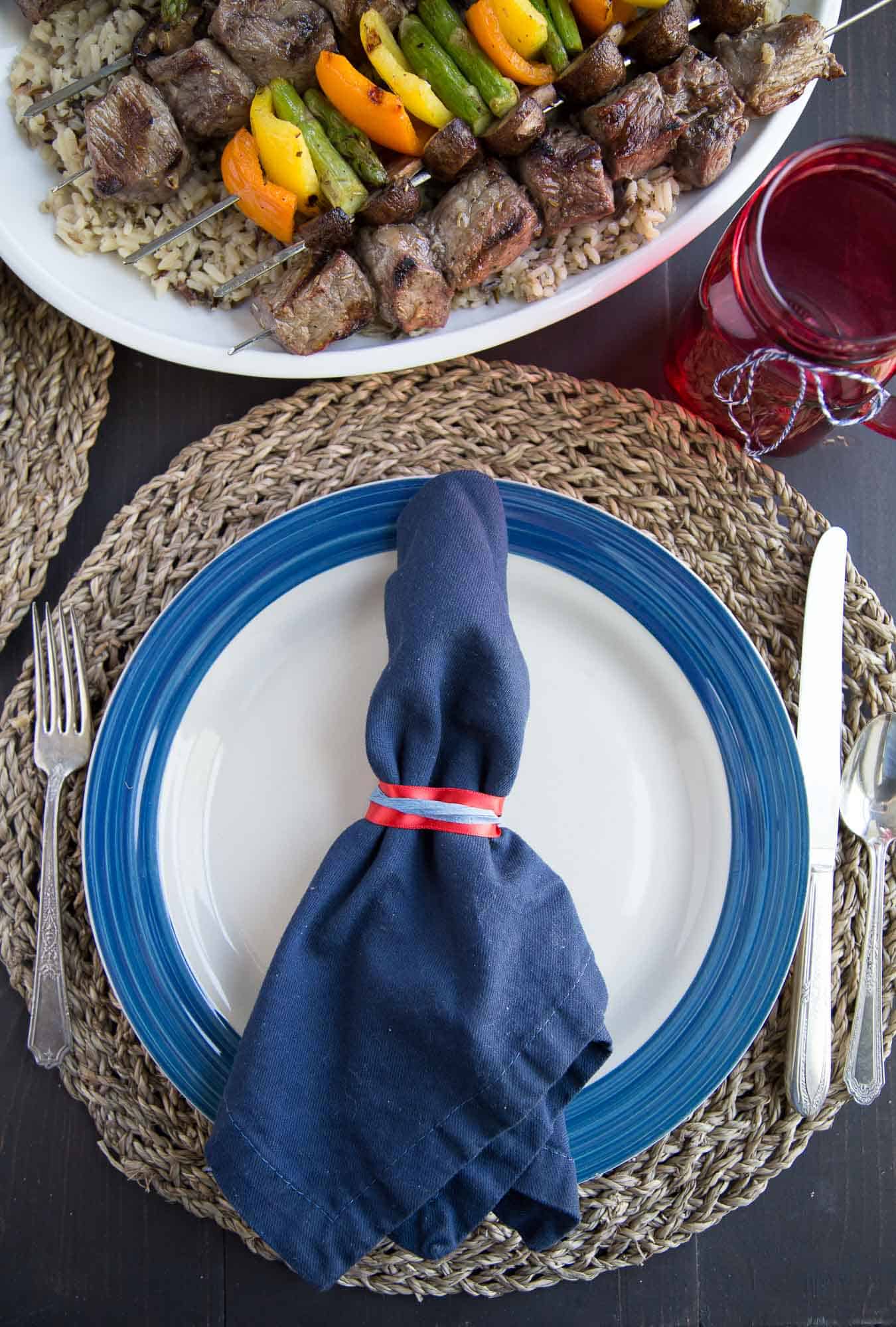 Tablesetting with blue cloth napkin, white and blue plate, and silverware.