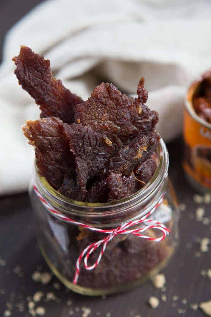 homemade beef jerky in a glass jar with a red and white ribbon