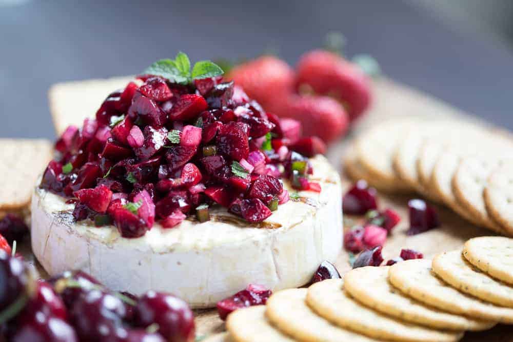 grilled brie topped with cherry salsa surrounded by fresh cherries and crackers