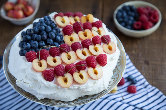 patriotic pavlova on a cake stand on a wooden table