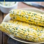 corn on the cob with herb butter in a beige bowl.