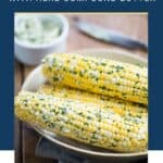 corn on the cob with herb butter in a beige bowl.