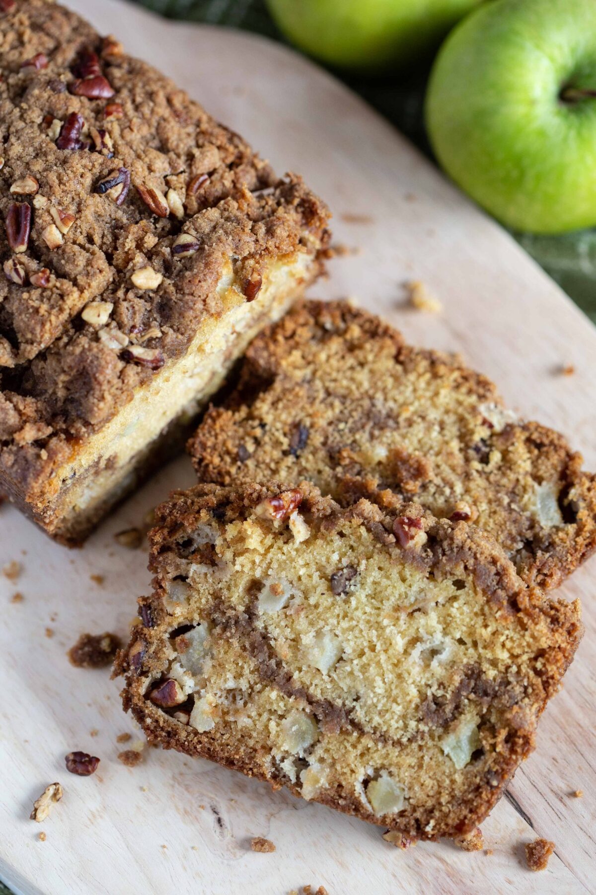 loaf of apple bread with a few slices cut out of it on a wooden board