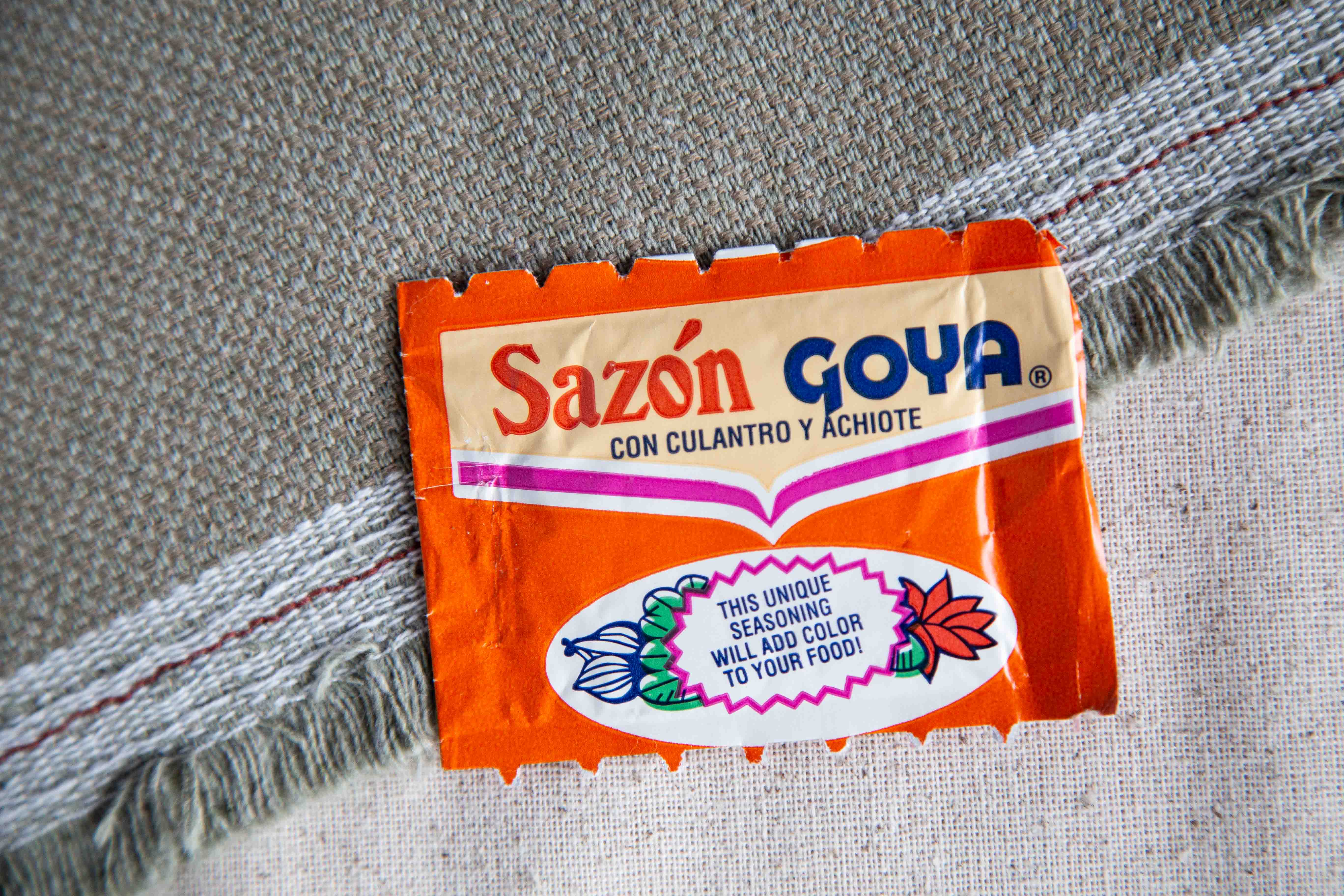 orange Goya Seasoning packet on a green and cream tablecloth