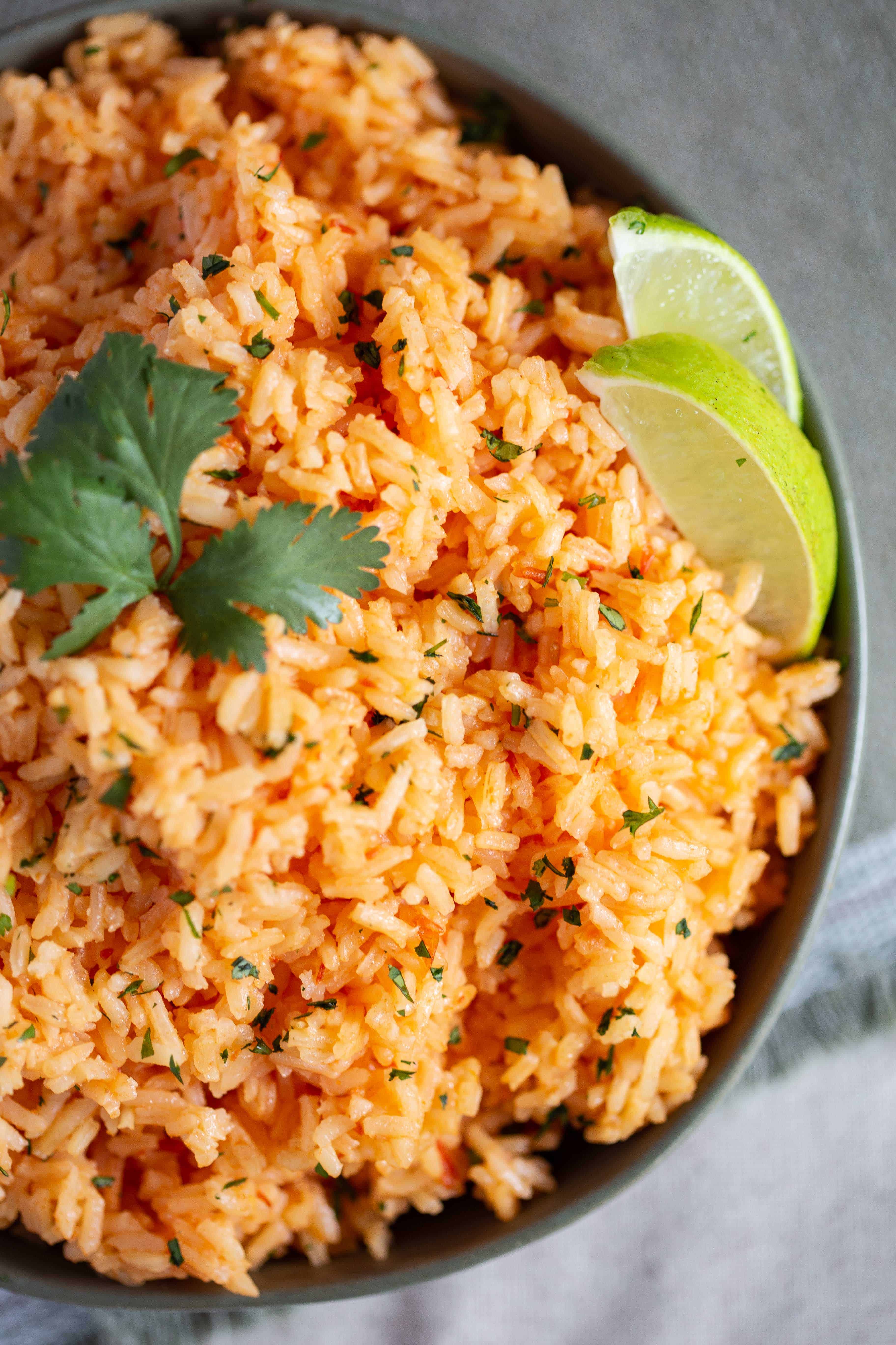 Authentic Mexican Rice with Cilantro in a green bowl, garnished with lime