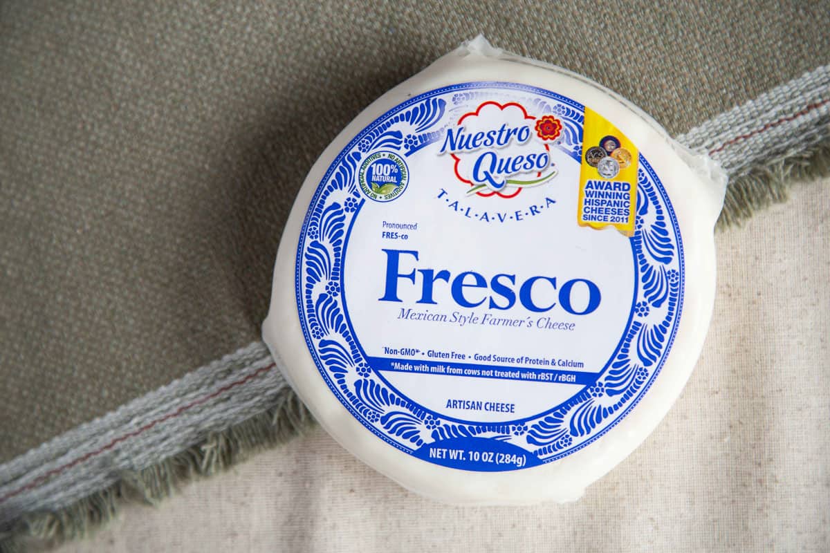 round package of queso fresco on a beige tablecloth.