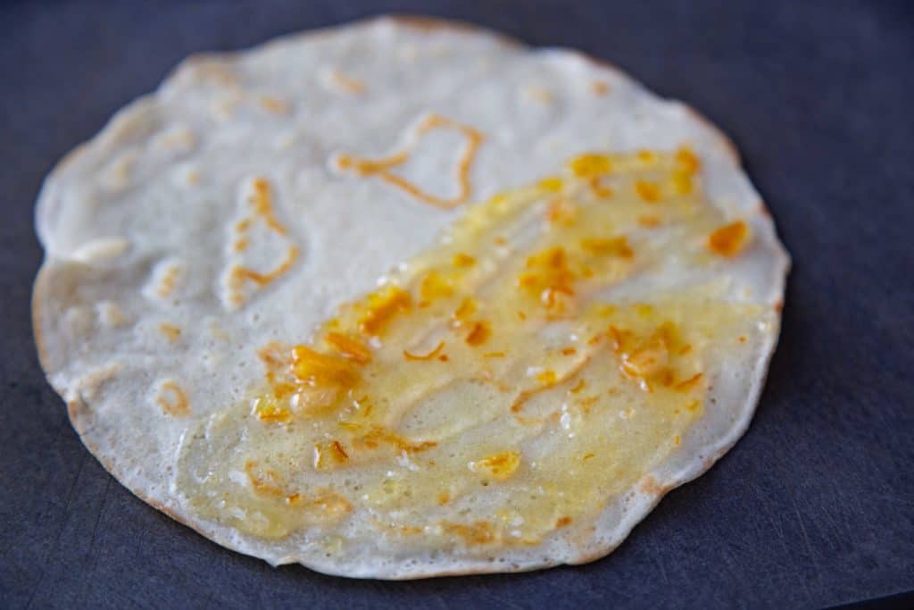 single crepe spread with orange jam on half of it.