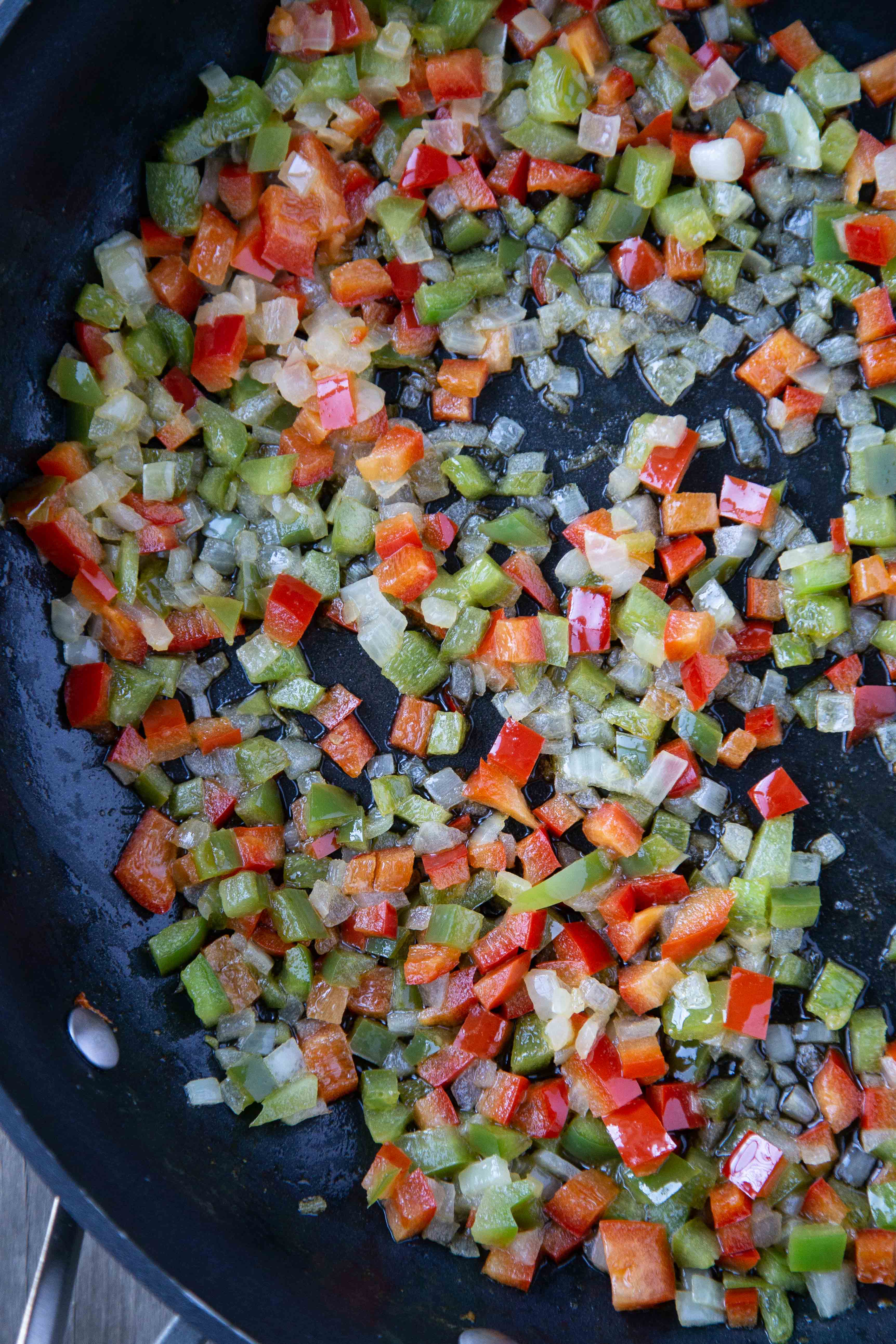 onions, red peppers, and poblano peppers cooking in a sauté pan