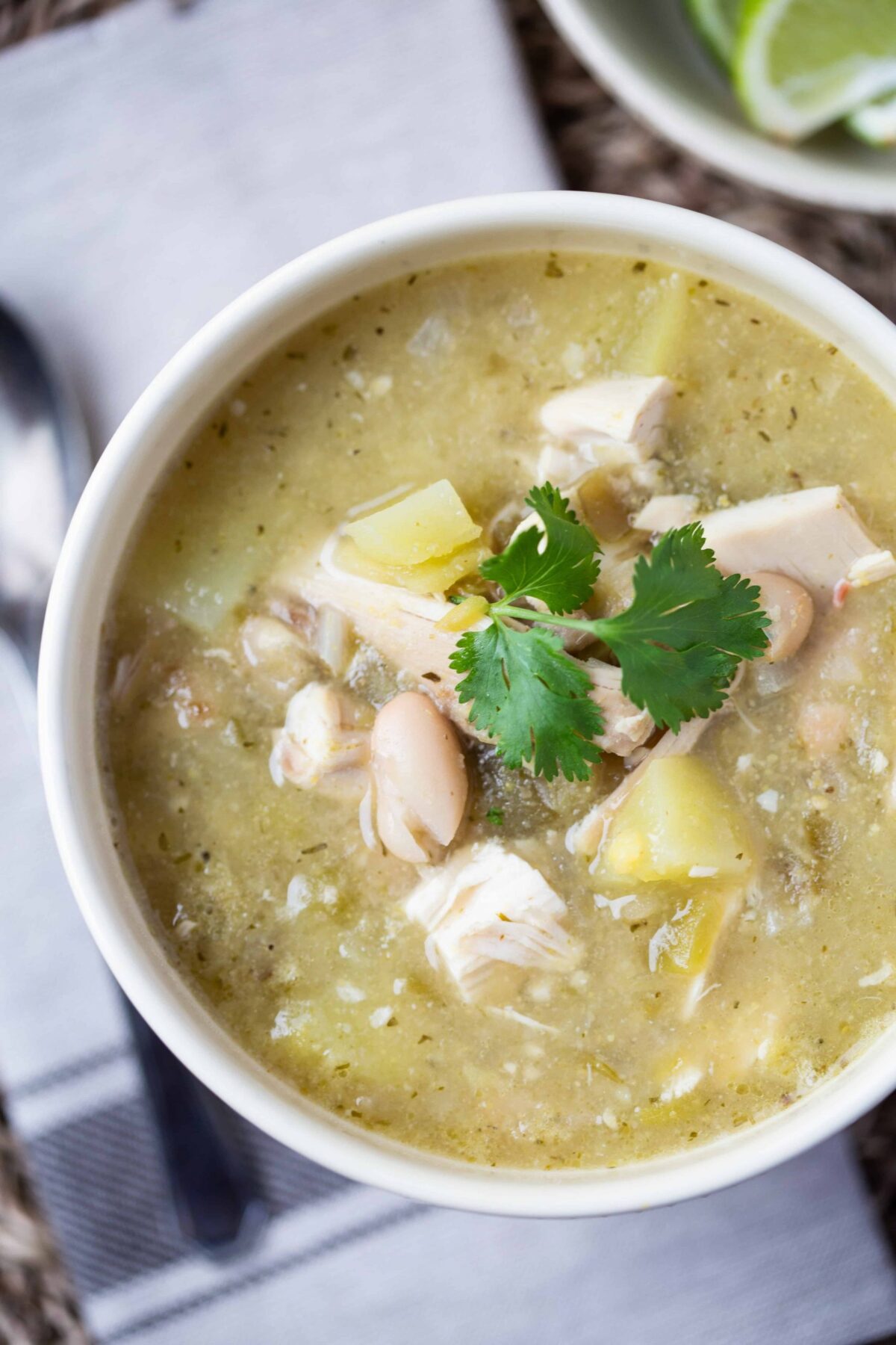 White Chicken Chili with Beans and Potatoes topped with cilantro in a yellow bowl