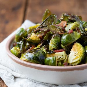 bacon brussels sprouts in a cream bowl on a wooden table.