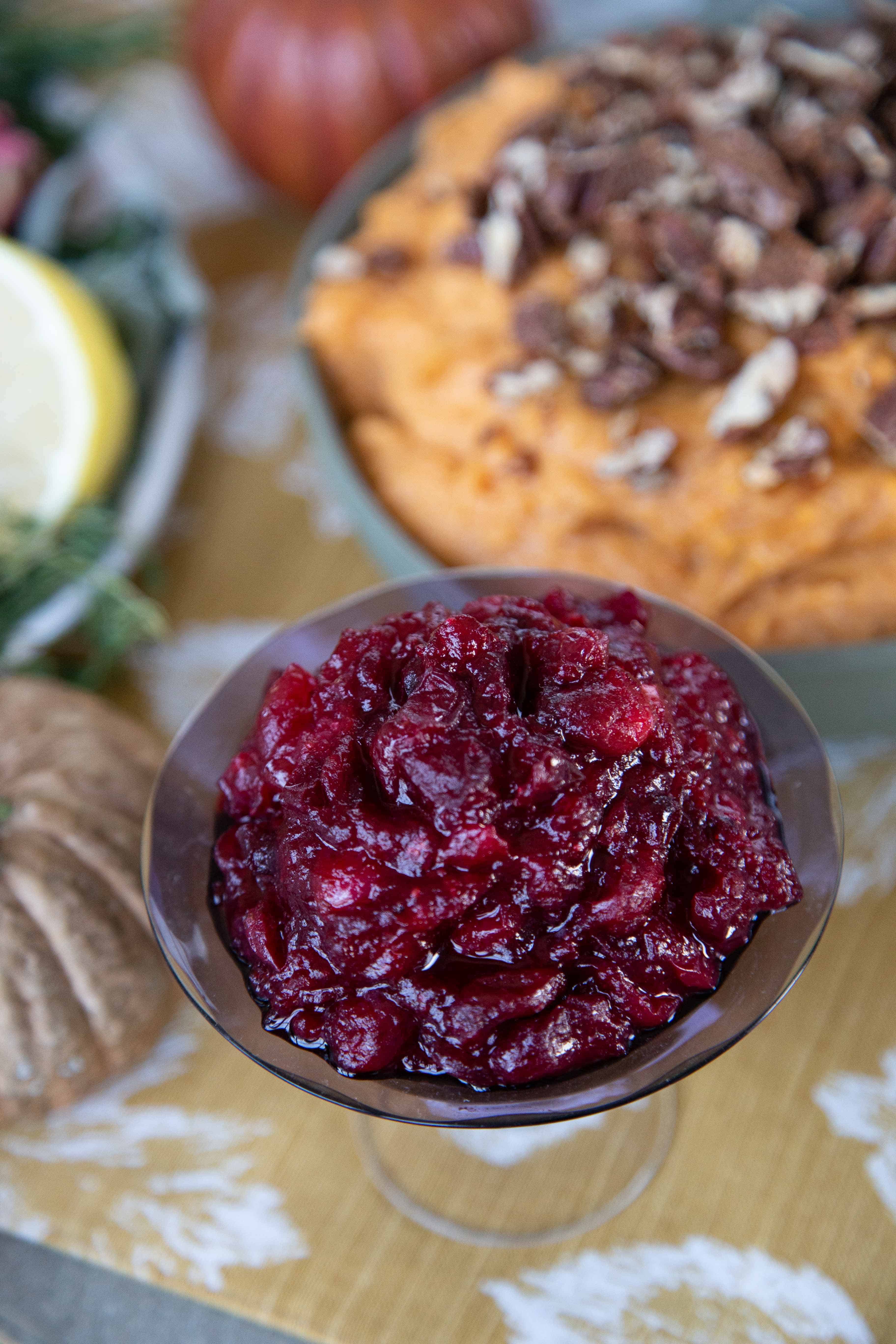 Apple Cranberry Sauce in a glass dish on a colorful Thanksgiving table.
