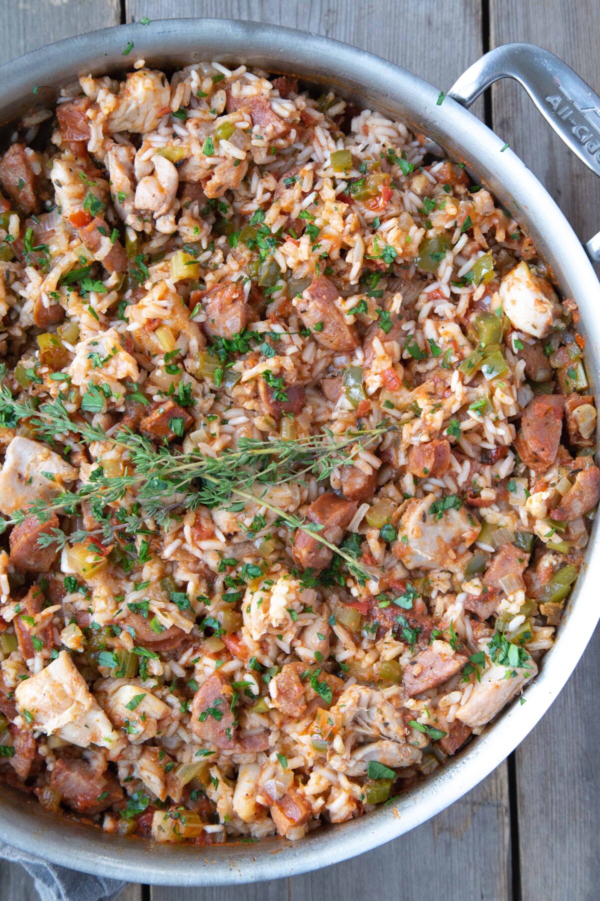 chicken and sausage Jambalaya in a large sauté pan, garnished with fresh thyme.