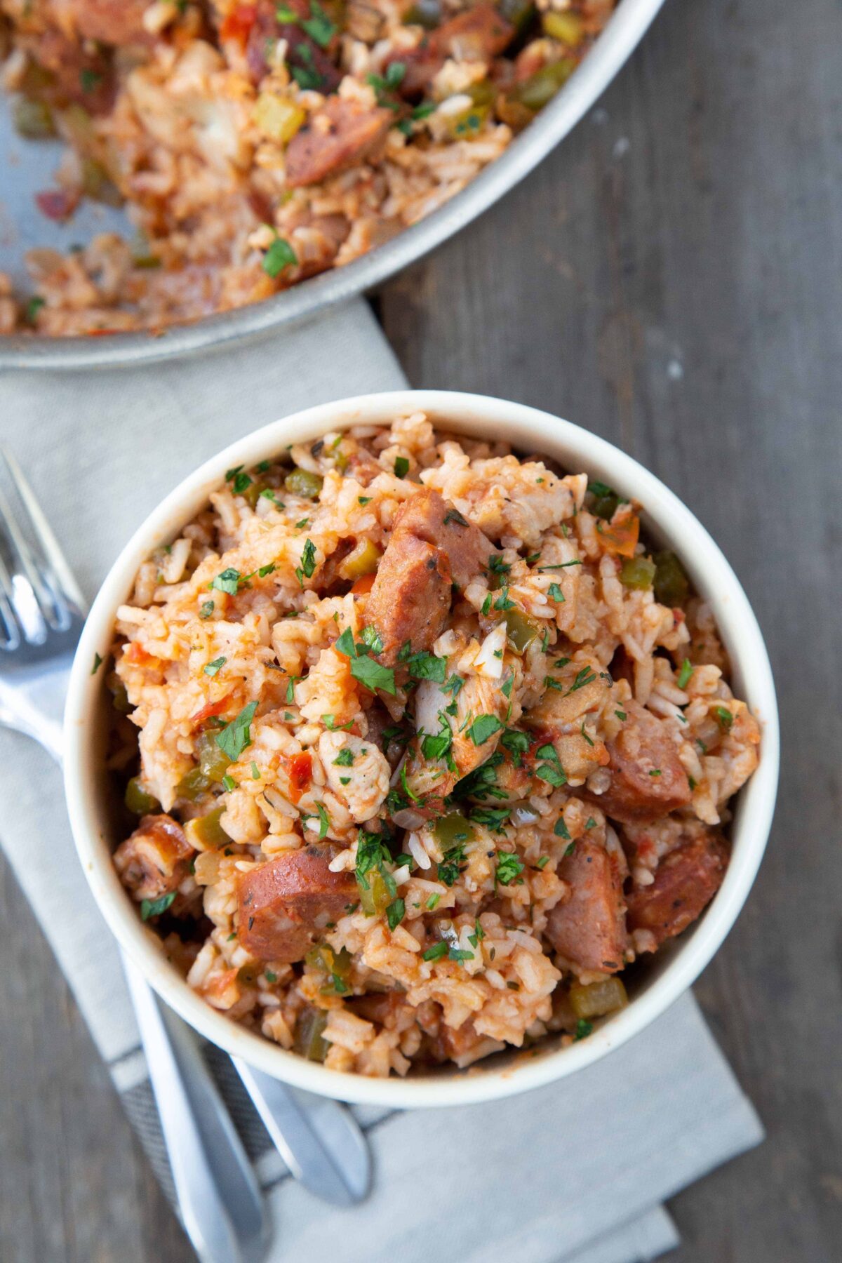 overhead view of a yellow bowl filled with chicken and sausage Jambalaya, topped with parsley.