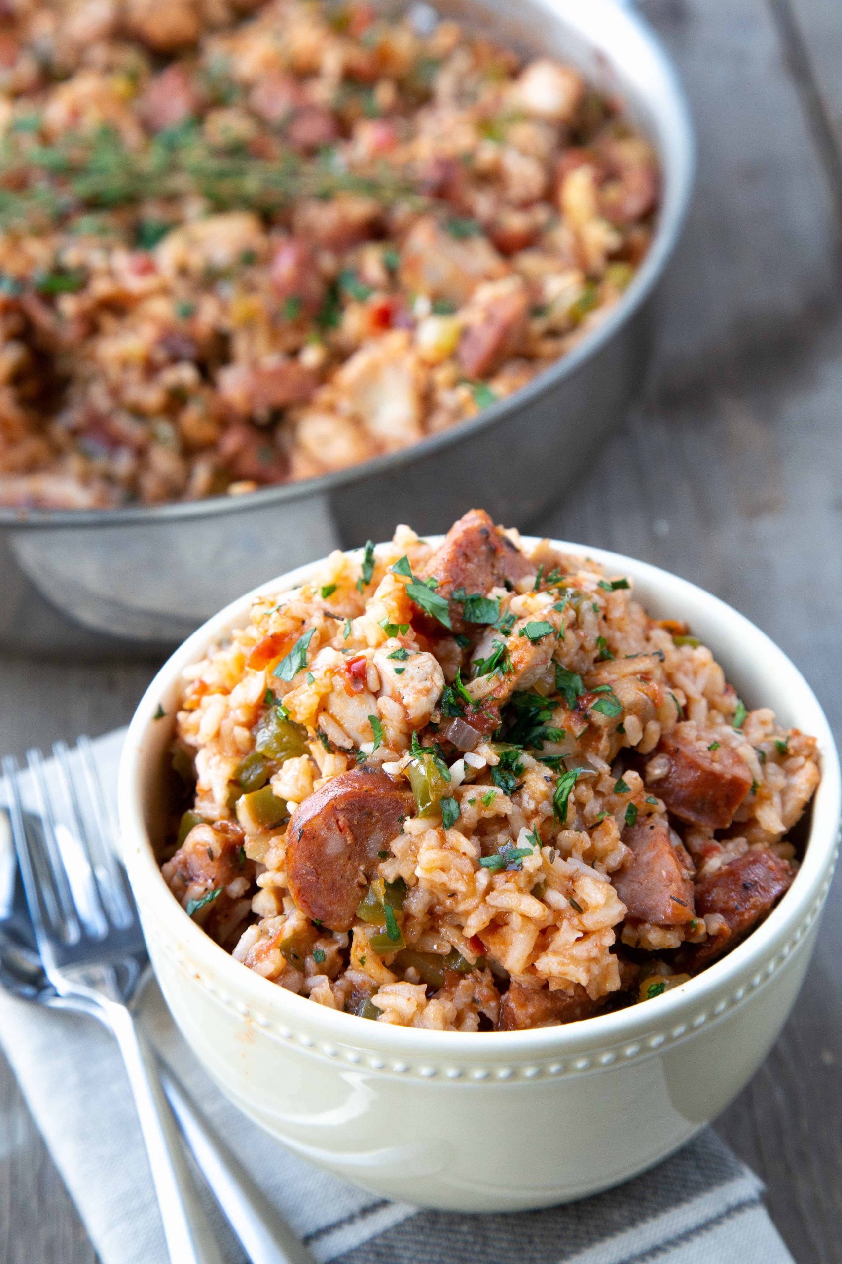 Quick Weeknight Jambalaya in a yellow bowl with a pan of jambalaya in the background.