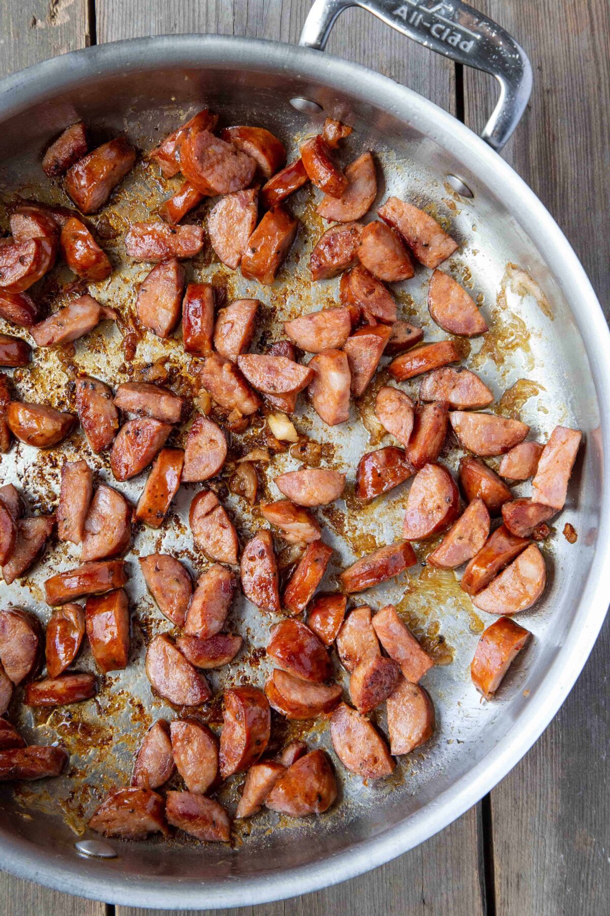 andouille sausage cooking in a large sauté pan.