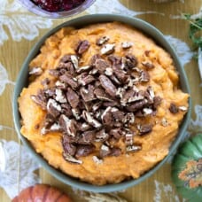 a green bowl filled with mashed sweet potatoes, topped with candied pecans.