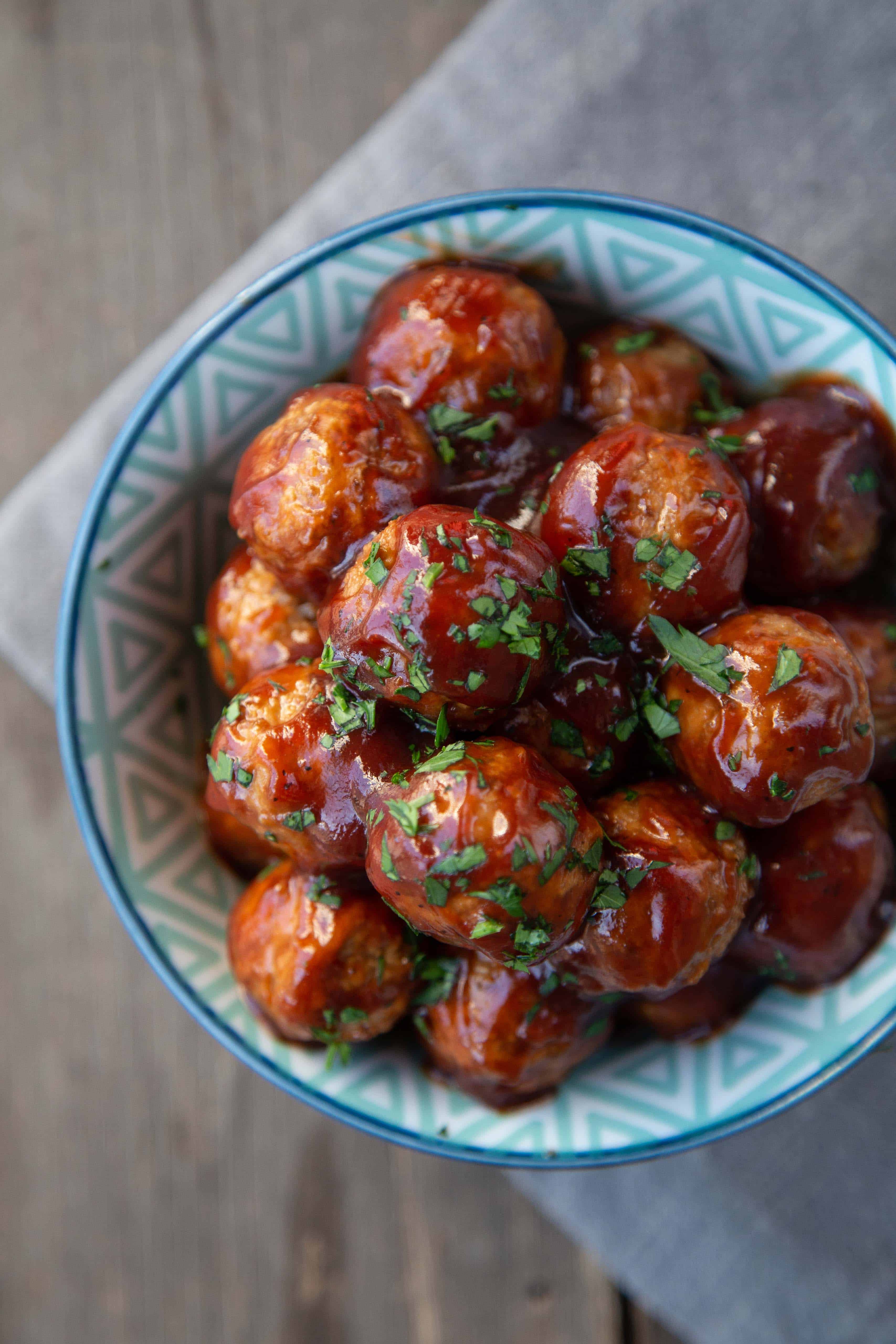 BBQ meatballs in a blue patterned bowl, topped with parsley.