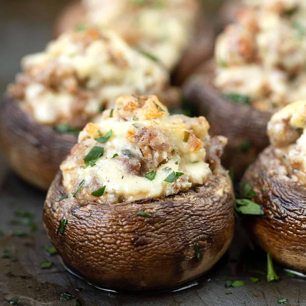 mushrooms stuffed with sausage and boursin cheese, sitting on a metal sheet tray.