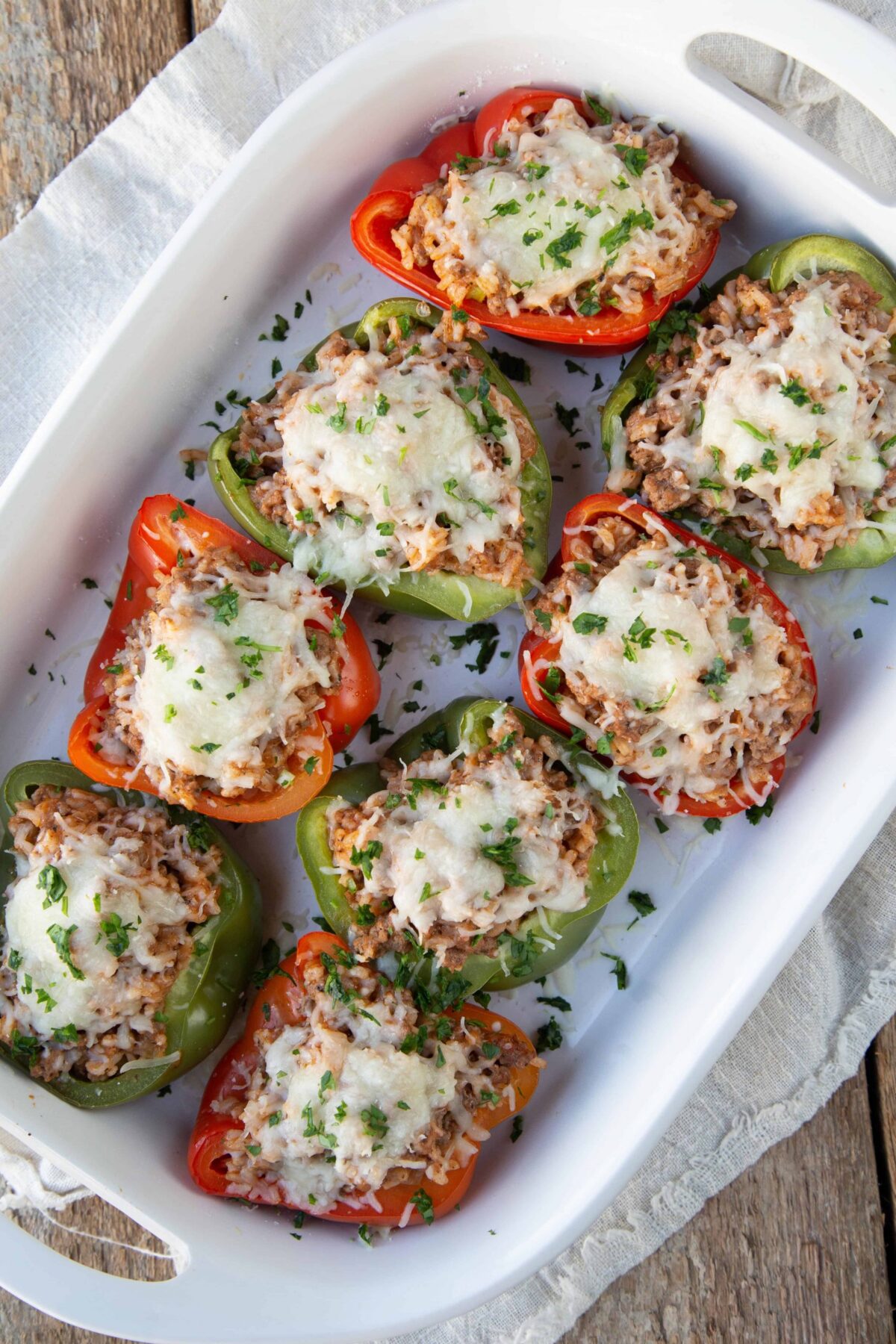 Italian Stuffed Peppers topped with cheese in a white baking dish.