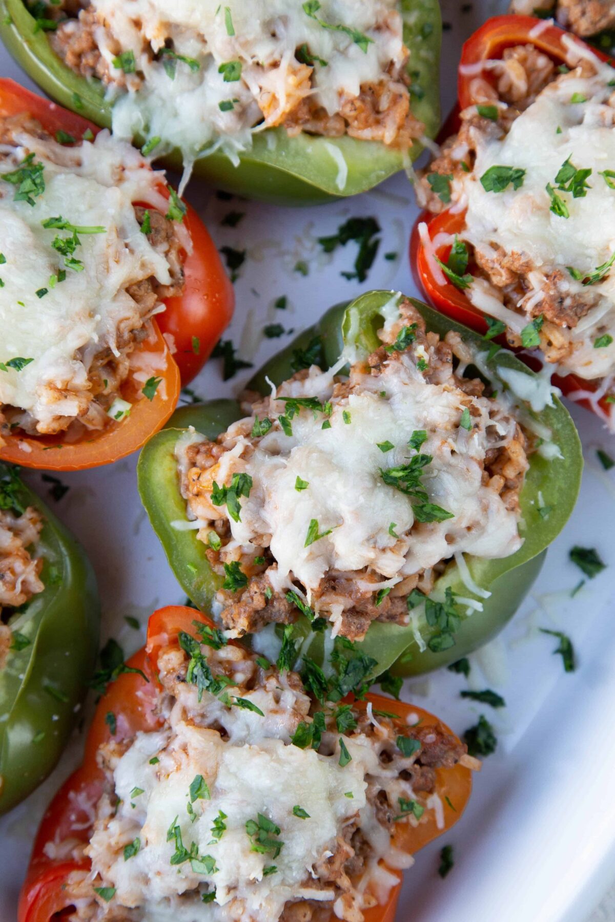 red and green stuffed peppers topped with cheese in a white casserole dish