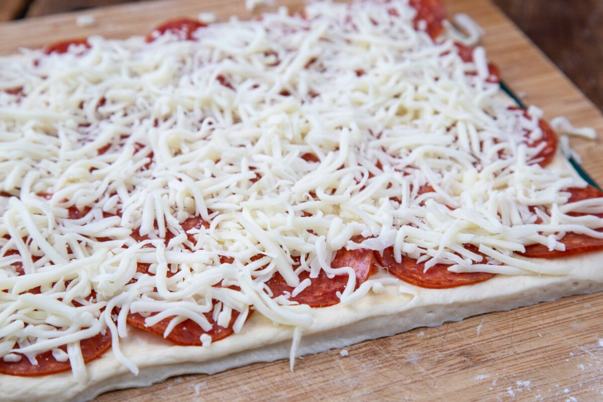 pizza dough topped with pepperoni and shredded cheese.