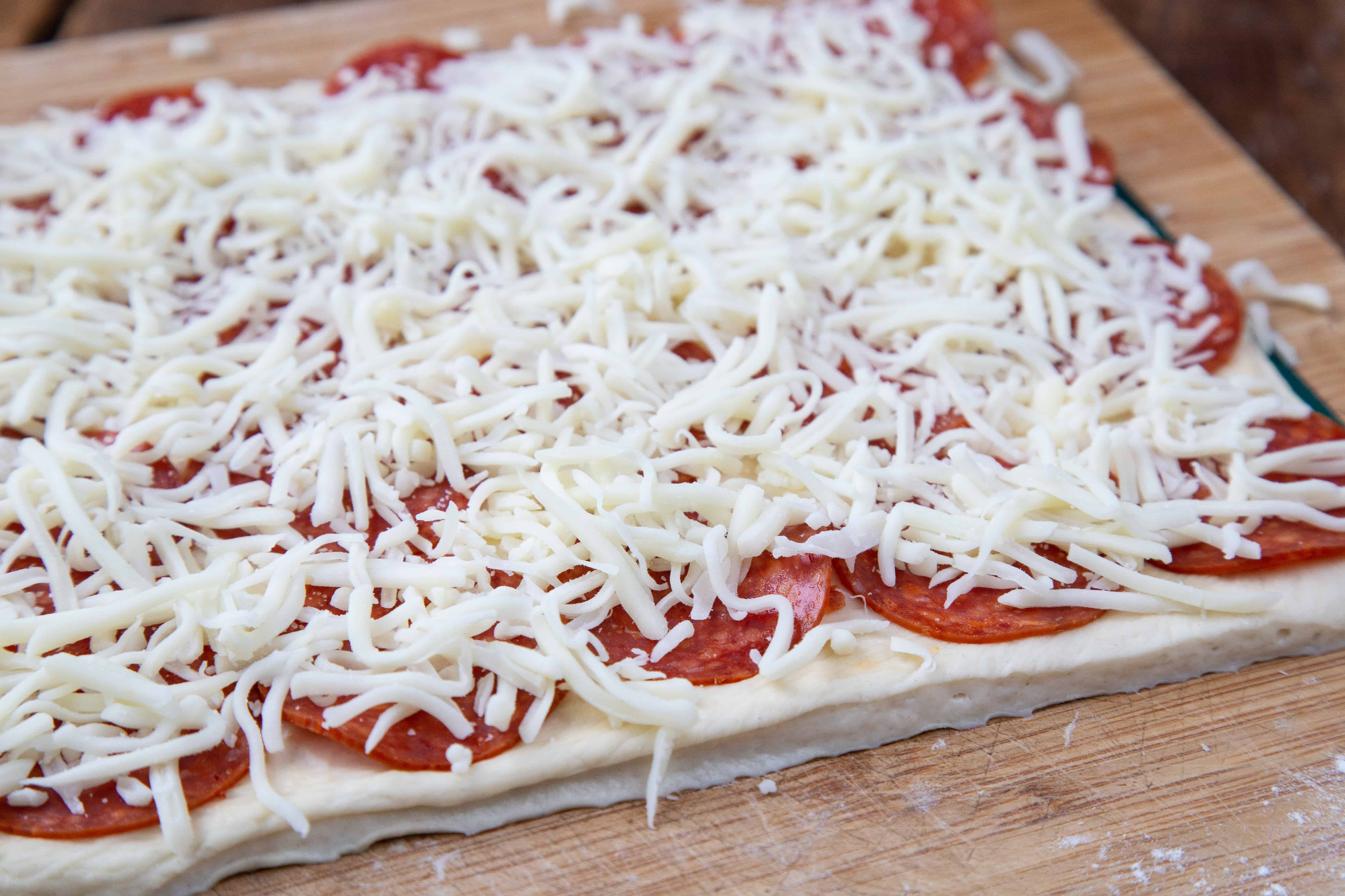 rectangle of pizza dough with pepperoni and cheese on top.
