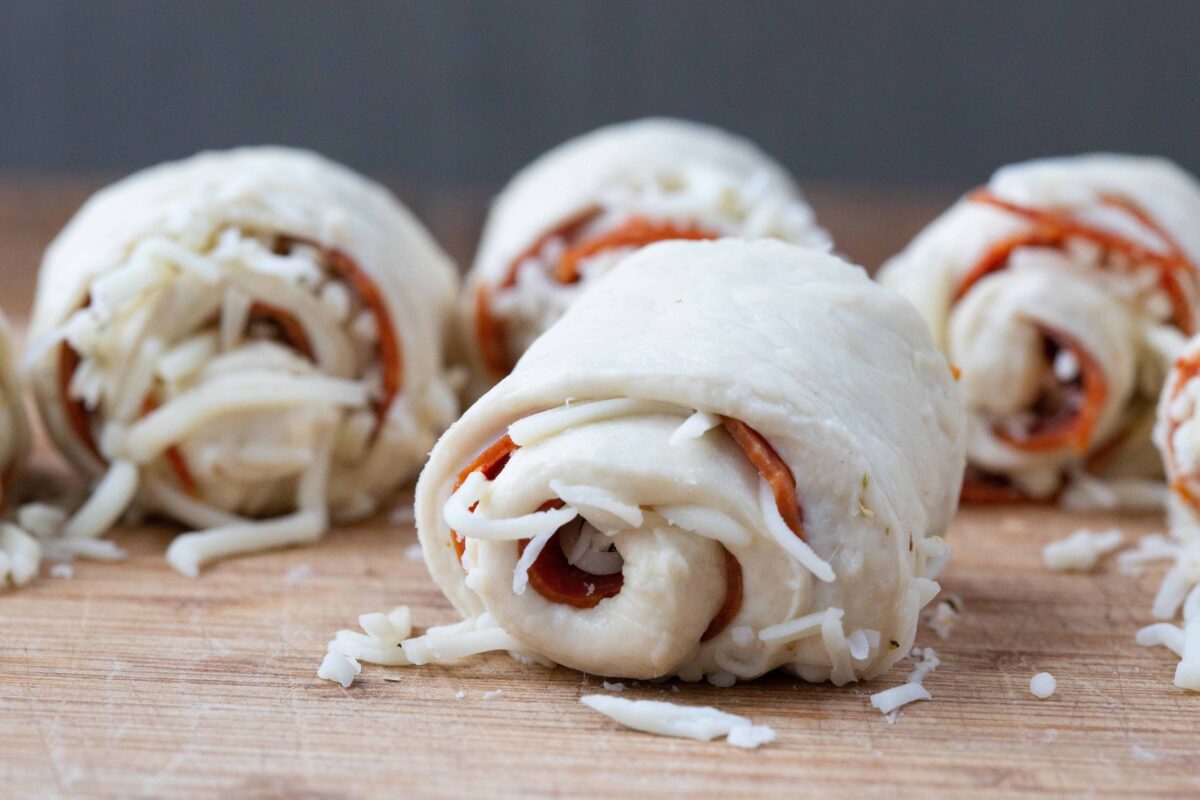 uncooked pepperoni rolls on a cutting board.