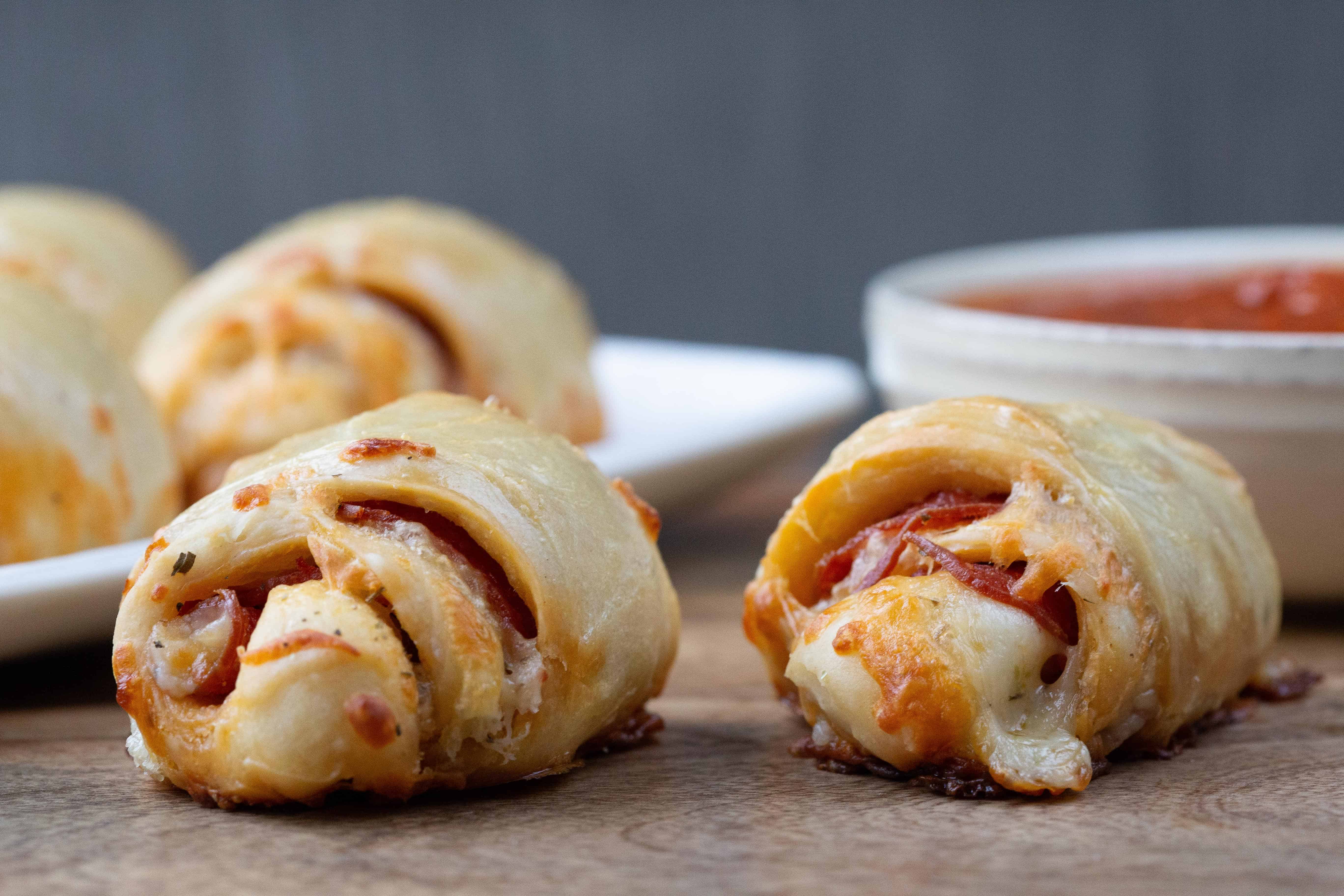 pepperoni rolls on a wooden board with a small dish of marinara.