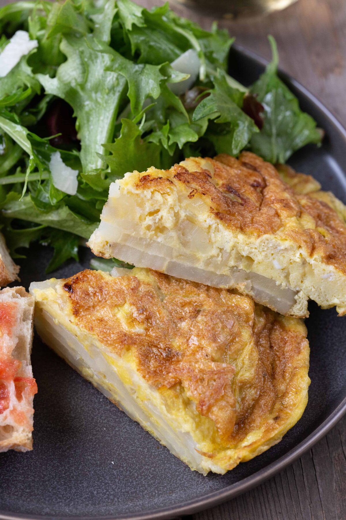 Tortilla Espanola (Spanish Potato Omelette) on a plate with a leafy green salad.