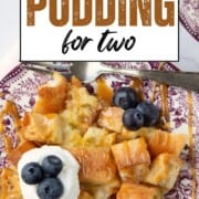 slice of bread pudding with pieces of cubed bread, topped with whipped cream and blueberries.