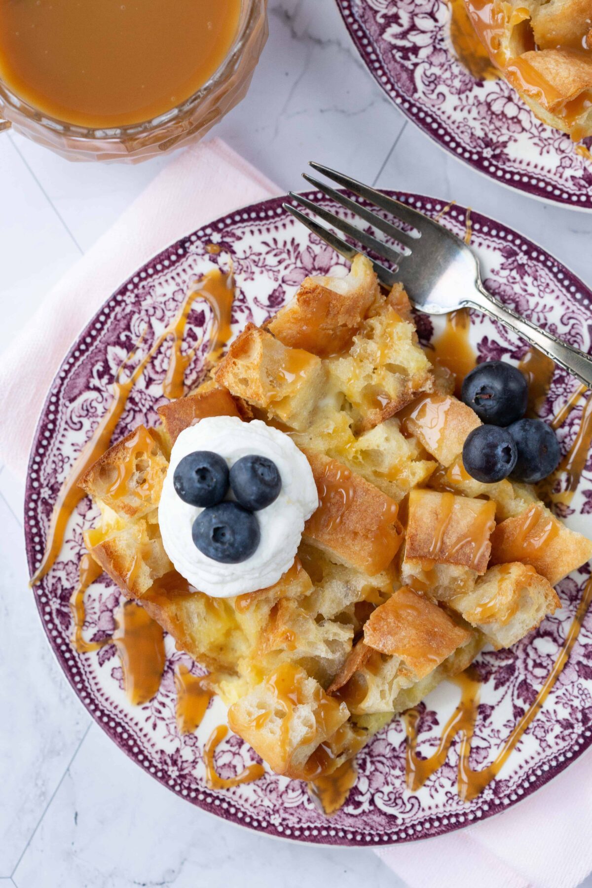 blueberries and whipped cream on top of a slice of bread pudding.