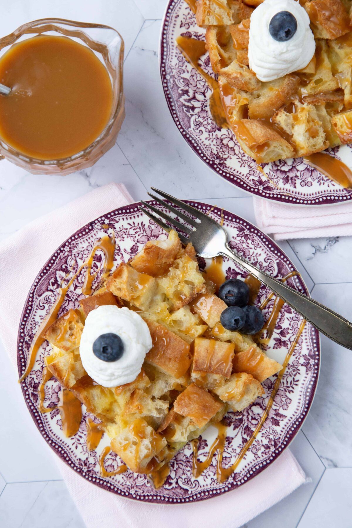 Bread Pudding for two slice on a plate with blueberries and whipped cream.