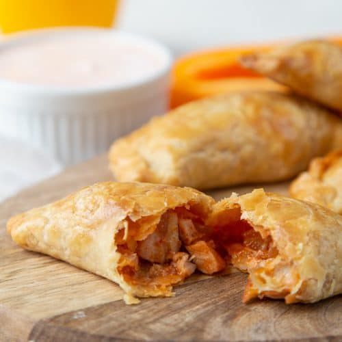 chicken enchilada empanada split open on a wooden board.