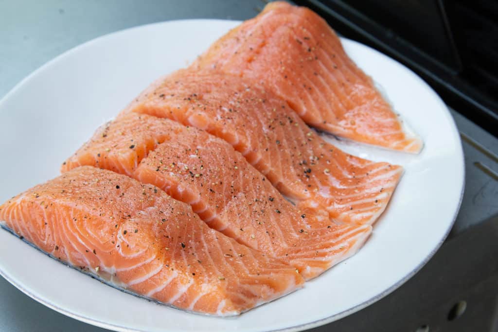 Four salmon fillets on a white plate