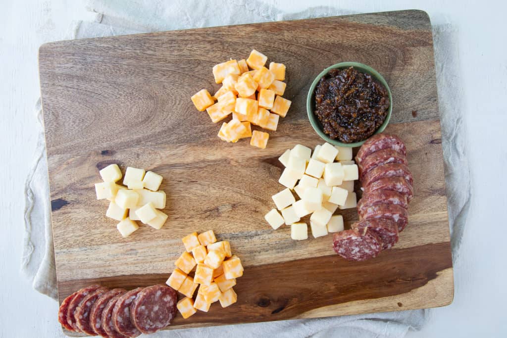 Wooden board with cheese cubes and salami
