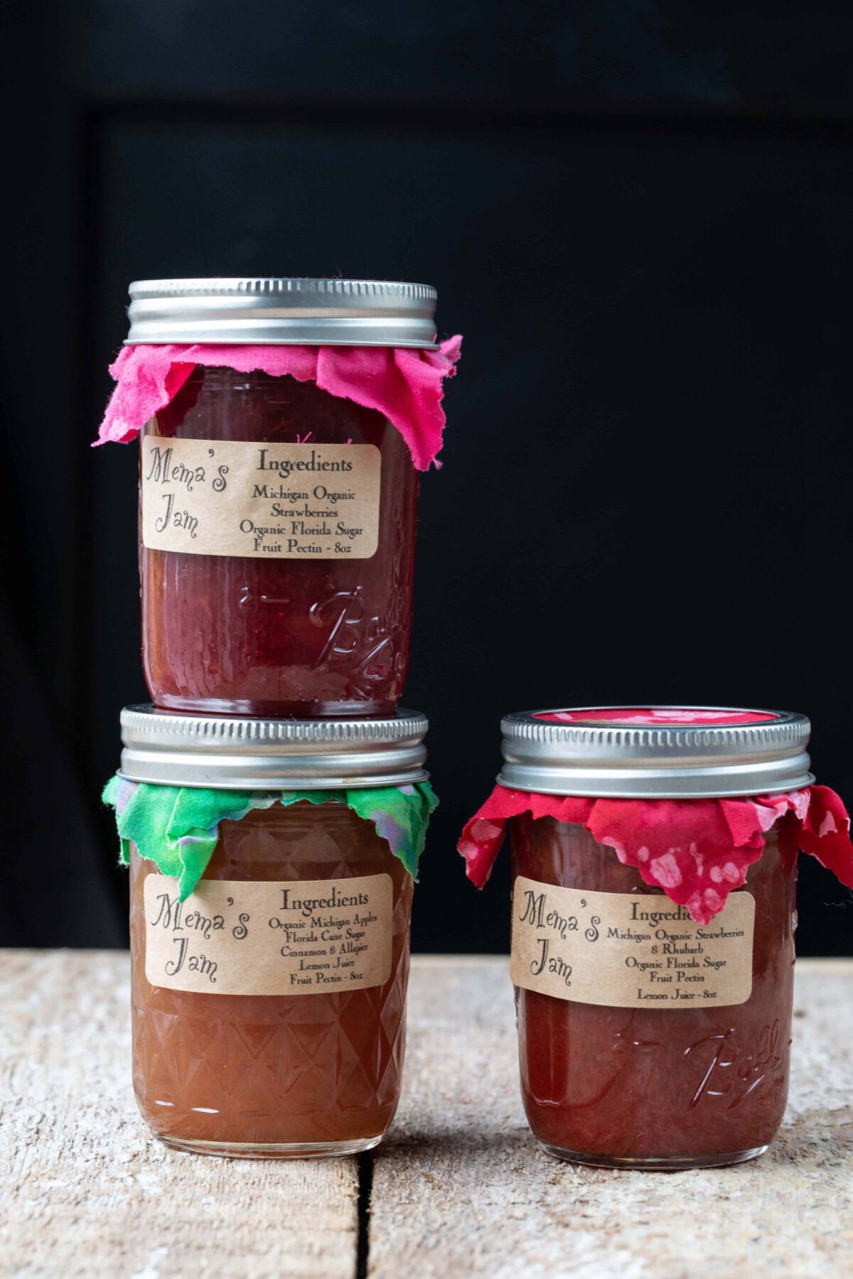 three jars of jam in mason jars with fabric lid toppers.