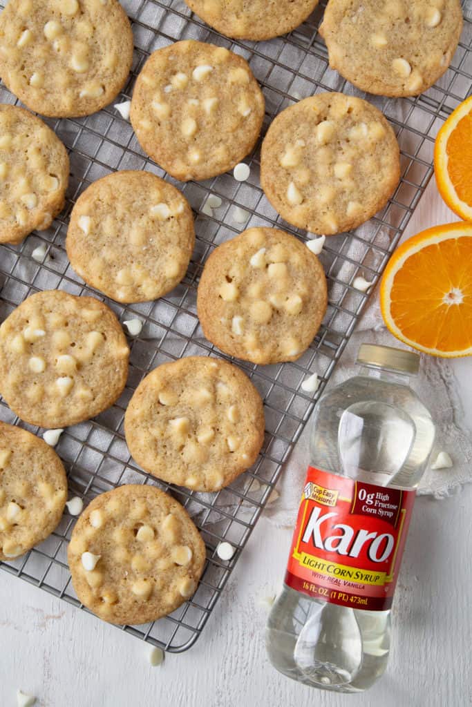 Chewy White Chocolate Orange Cookies on a cooling rack with a bottle of corn syrup on the side.