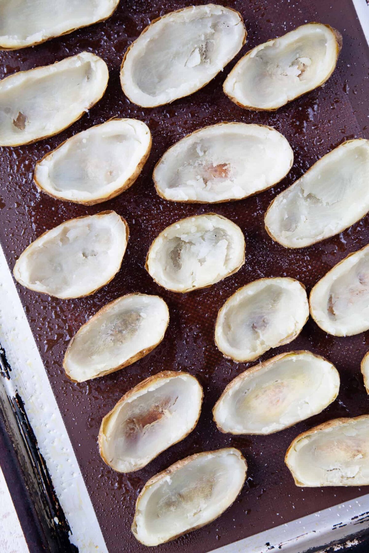 Hollowed out potatoes on a baking sheet.