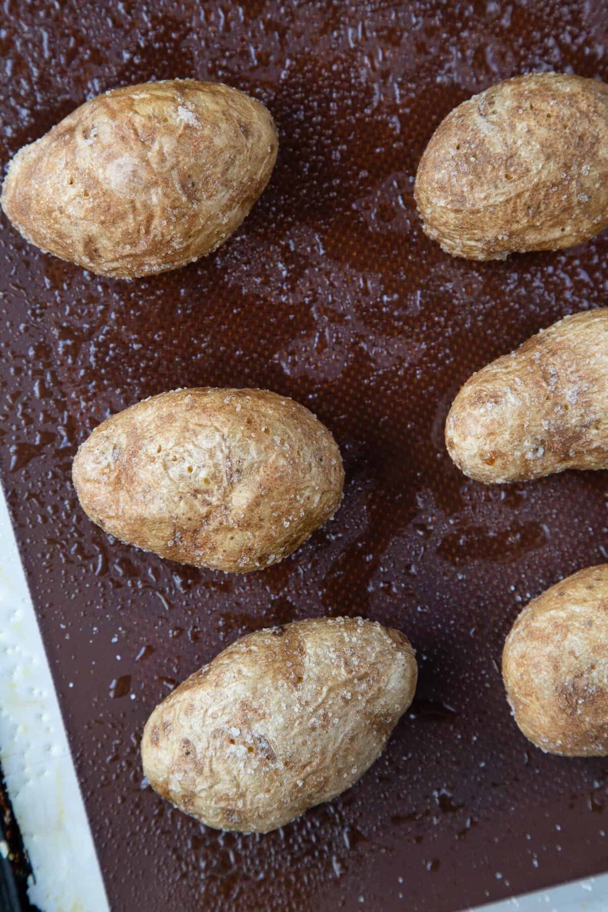Roasted whole potatoes on a baking sheet.