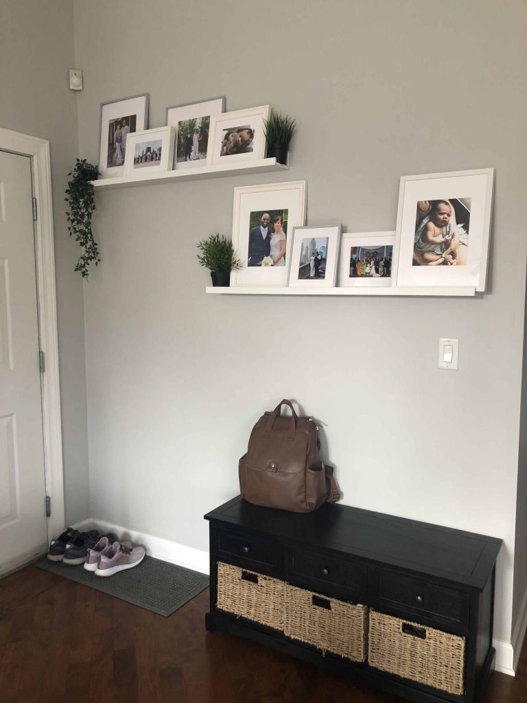 entryway with a black bench and photos on the wall.