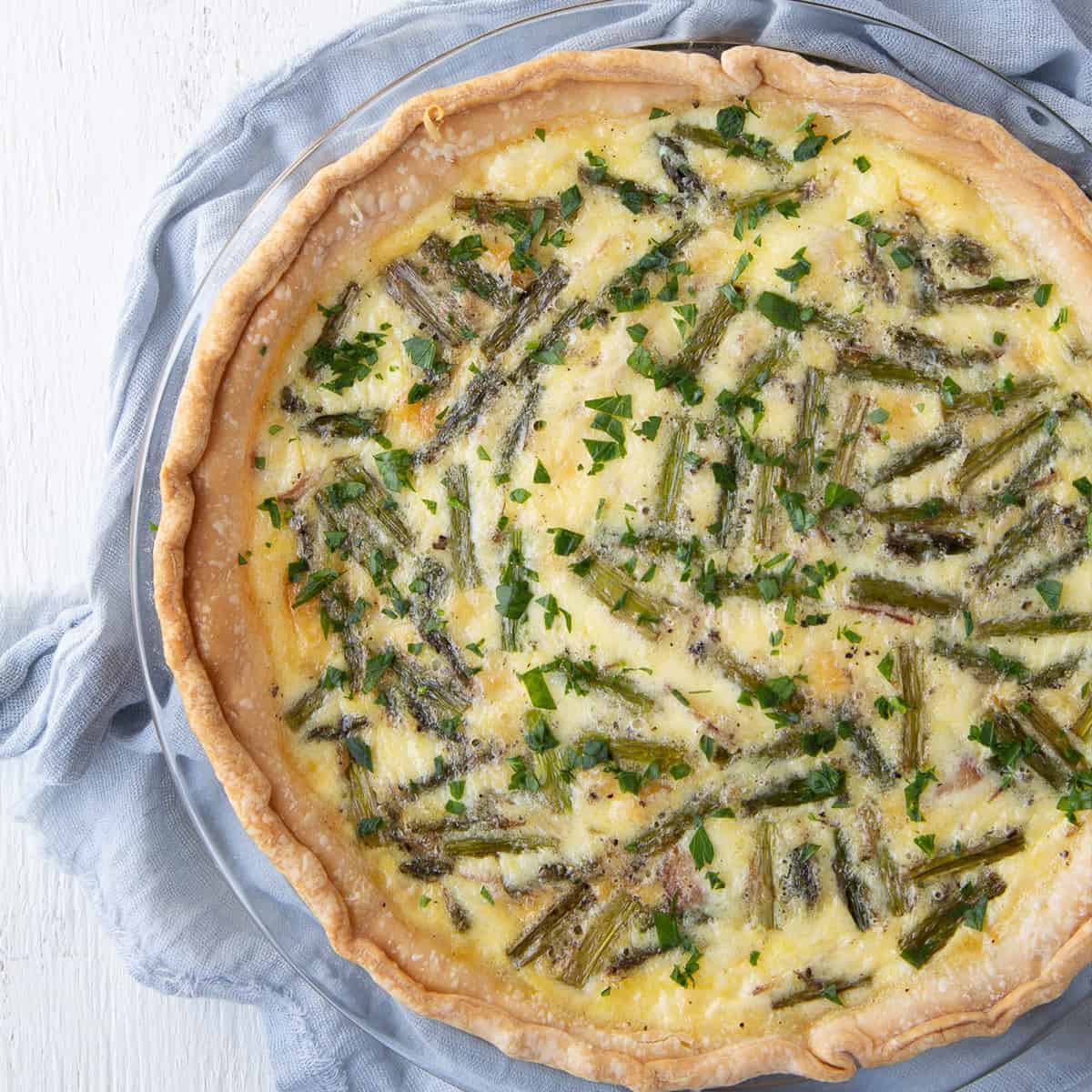 asparagus quiche sitting on a blue tea towel.