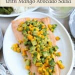 side of salmon on a white platter with mango and avocado salsa on top