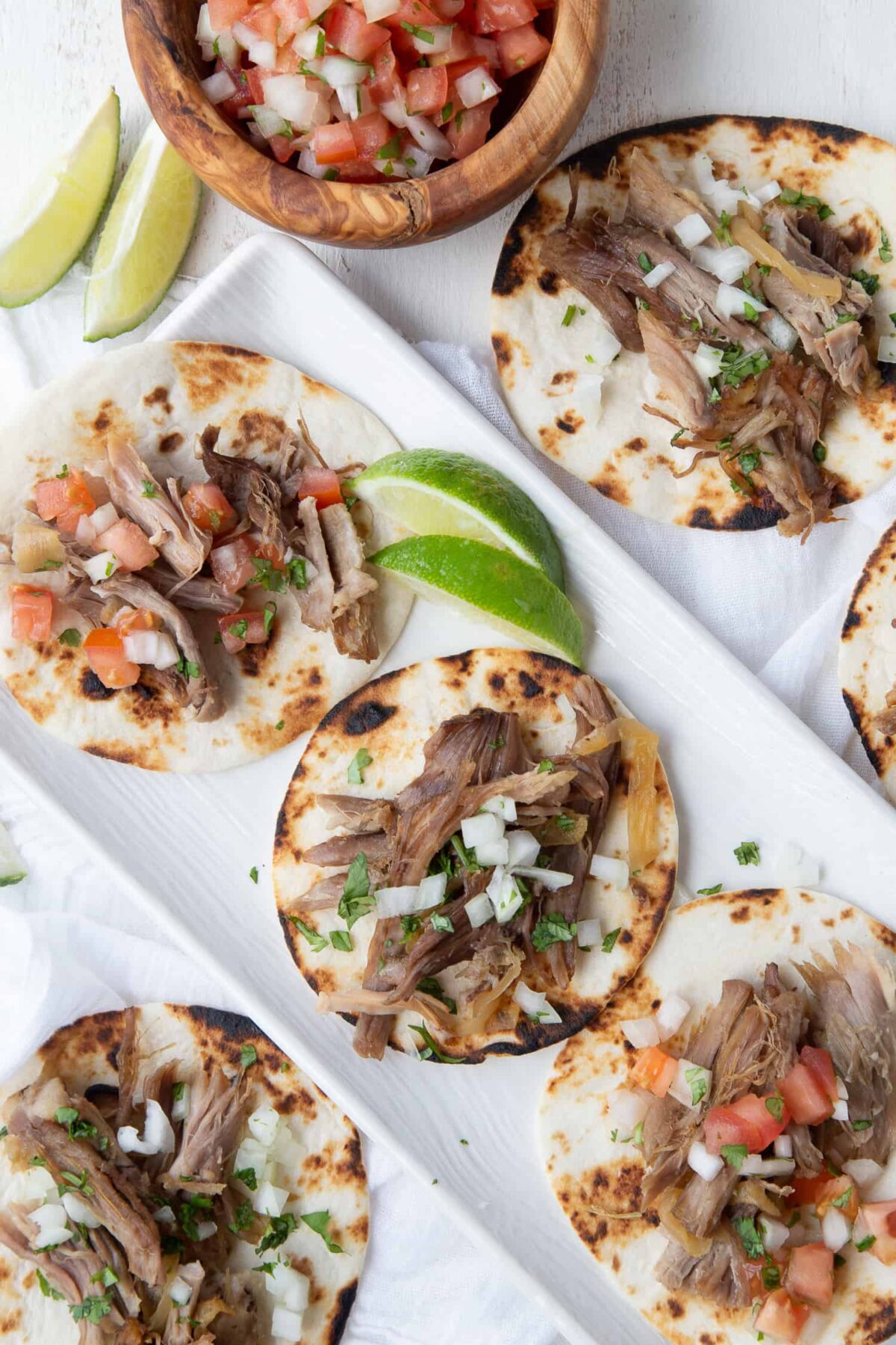 carnitas on mini flour tortillas topped with onion, cilantro, and pico de gallo.