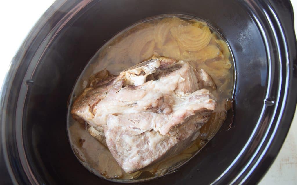 cooked whole pork shoulder and onions in a slow cooker.