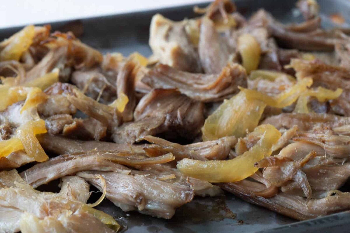 carnitas and onions on a sheet pan with crispy edges.