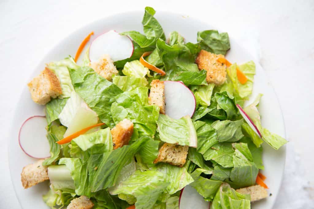 closeup of a green salad with radishes, carrots, and croutons
