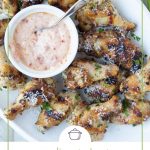 Garlic and herb wings on a white platter with a small white bowl of sun dried tomato mayo